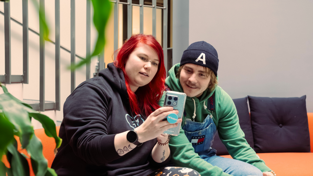 Sini ja Antti katsomassa yhdessä älypuhelinta, joka on Sinin kädessä.